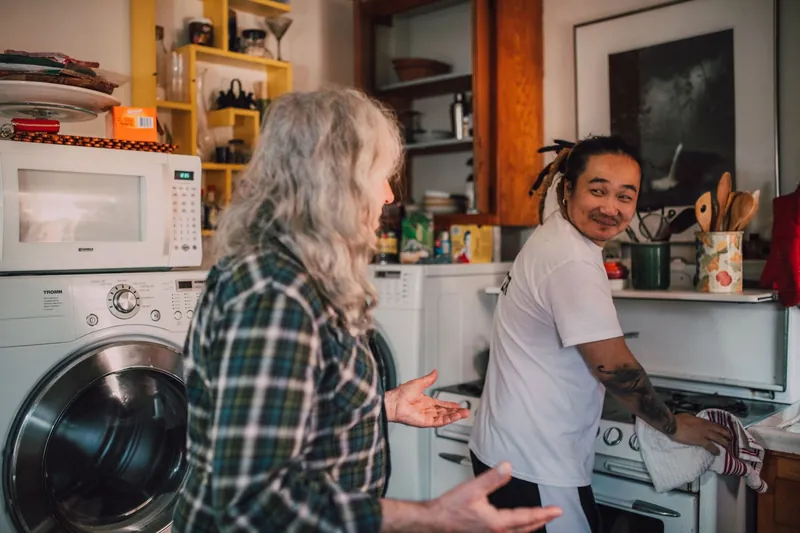 Un Butler nettoie la cuisinière pendant que la résidente lui parle