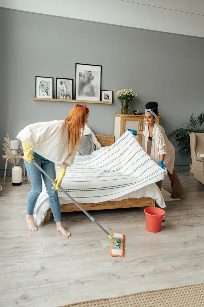 Deux Butlers font le lit et passent la vadrouille dans une chambre lumineuse